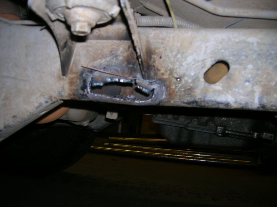 Close-up of a vehicle frame with cutouts and visible welding marks