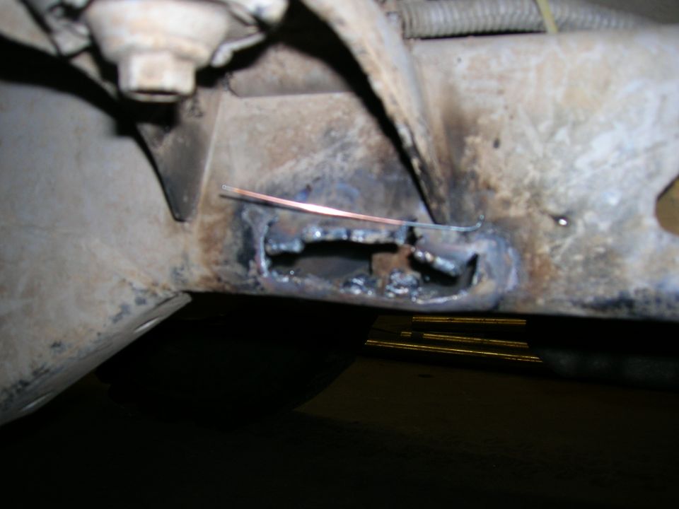 close-up of a vehicle frame with a hole cut into it and evidence of welding