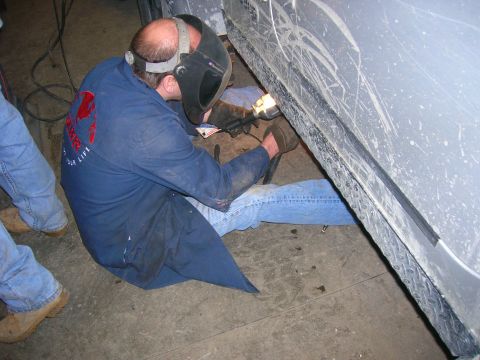 2003 Jeep TJ - A person in a welding mask works on the side of a vehicle's frame.