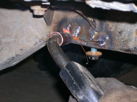 2003 Jeep TJ - Welding is performed on a damaged vehicle frame, with sparks flying from the torch.