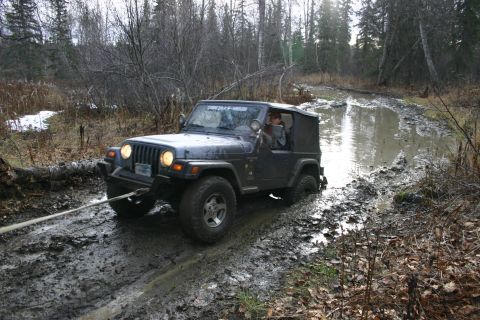 2003 Jeep TJ - 2003 Jeep TJ navigating a challenging muddy off-road path.