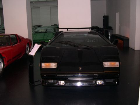2003 Jeep TJ - A black Lamborghini Countach is displayed in a showroom, with other classic cars visible in the background.