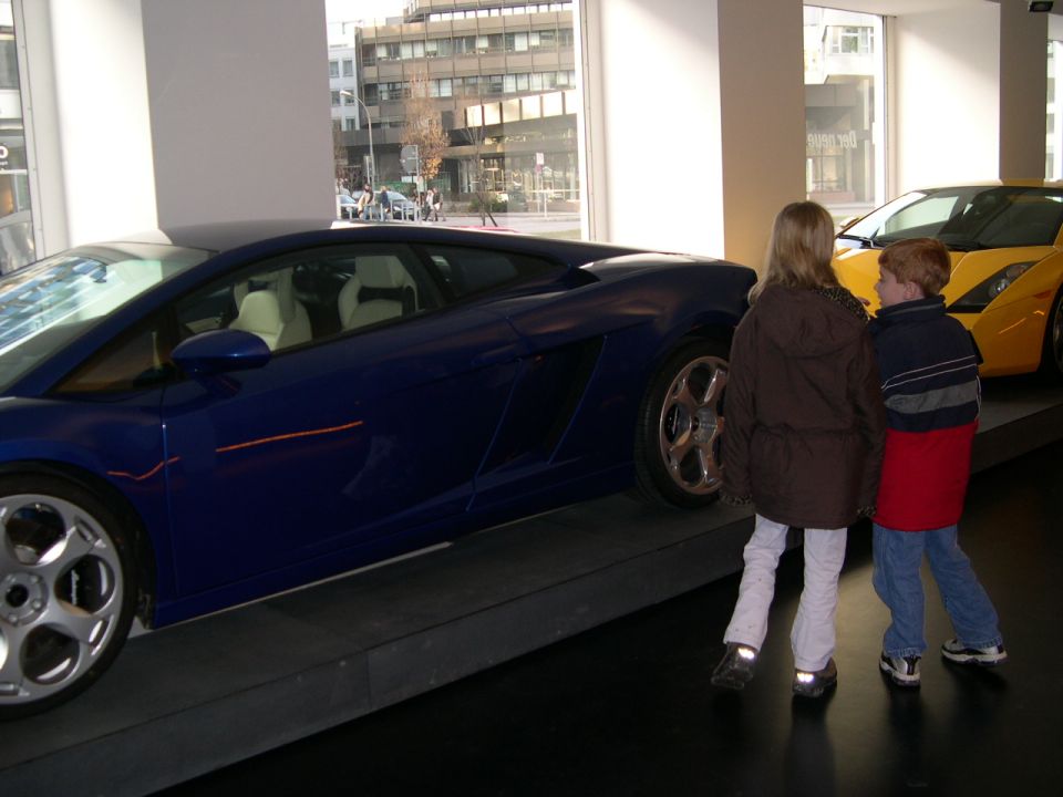 Blue sports car with white interior, viewed from the side, next to a yellow sports car