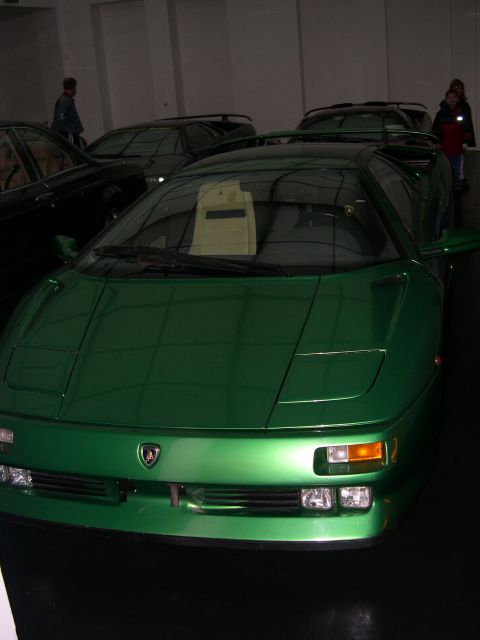2003 Jeep TJ - A green sports car is parked indoors with other vehicles visible in the background.