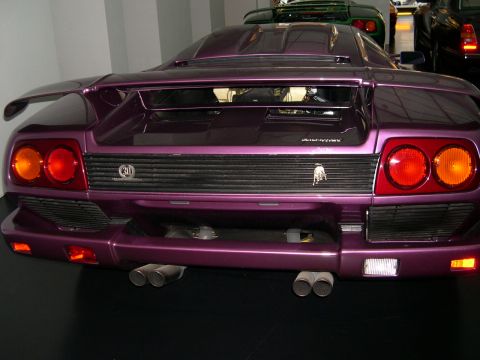 2003 Jeep TJ - Rear view of a purple Lamborghini Diablo, showing its quad exhaust and taillights. A green car is visible in the background.