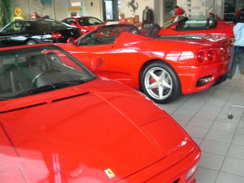2003 Jeep TJ - Several red sports cars are parked inside a showroom, with one in the foreground.