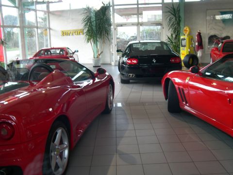 2003 Jeep TJ - Multiple red and black Ferrari sports cars are displayed in a dealership showroom.