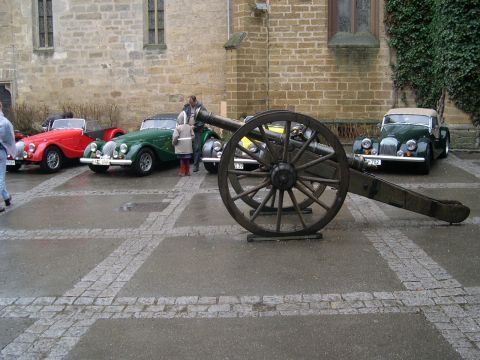 2003 Jeep TJ - Vintage cars and a cannon are displayed outside a stone building.