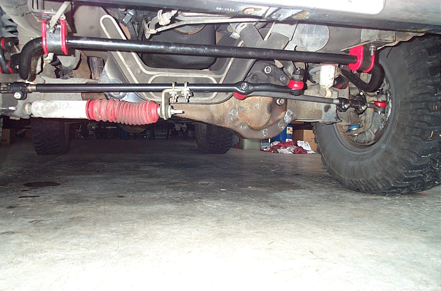 Underside front axle and steering linkage with red-booted stabilizer and off-road tires