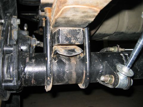 1985 Ford Bronco - Close-up view of a rear axle leaf spring mount, showing U-bolts and a shock absorber attachment point.
