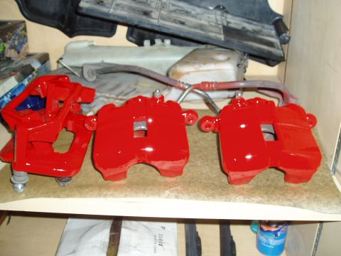 1993 Ford Taurus - Newly painted red brake calipers are displayed on a shelf, ready for installation.