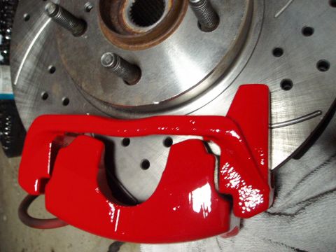 1993 Ford Taurus - Newly painted red brake caliper installed over a drilled brake rotor.