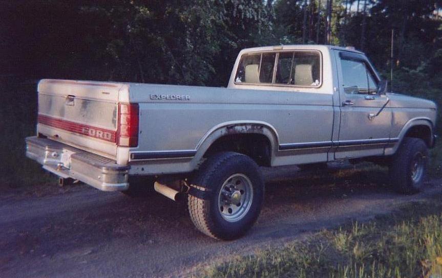 Silver Ford pickup with 'Explorer' on the bed, lifted with large tires