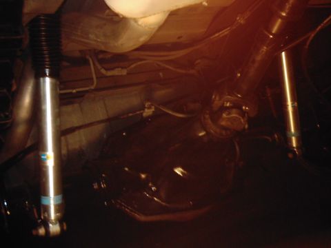 1978 Ford Bronco - Undercarriage components, including shock absorbers and drivetrain, are visible in this dimly lit photograph.