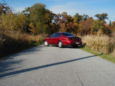 1997 Ford Taurus - Red 1997 Ford Taurus parked on a road during autumn.