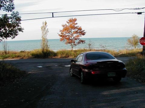 1997 Ford Taurus - 1997 Ford Taurus parked near a body of water with fall foliage visible.