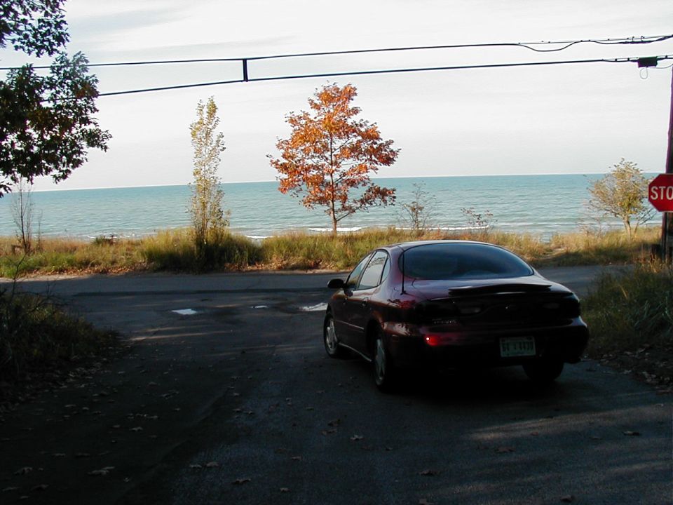 Dark red 1997 Ford Taurus parked on a road overlooking a lake