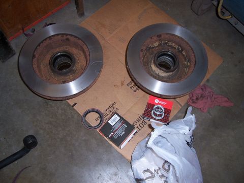 1983 Ford Bronco - Two brake rotors and associated parts are laid out on a cardboard box, likely for a vehicle repair.