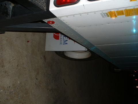 1989 Ford Thunderbird - Underside view of a trailer chassis, showing a tire and a metal plate with lease company branding.