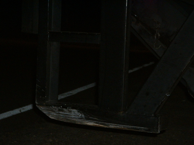 Close-up of a dark metal frame with scuff marks on the bottom edge