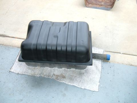 1983 Ford Bronco - A black plastic fuel tank is shown from a side angle, resting on a cloth on a concrete surface.