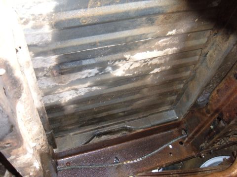 1983 Ford Bronco - Underside view of a rusty truck bed, showing the ribbed flooring and frame structure.