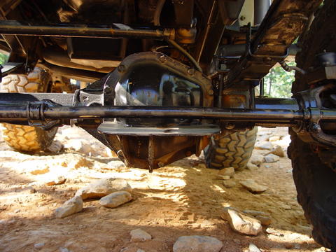 1996 Ford Bronco - The underside of a vehicle shows its differential and suspension components against a backdrop of rocks and sand.