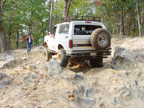 1996 Ford Bronco - White 1996 Ford Bronco navigates a challenging rocky trail, its off-road capabilities.