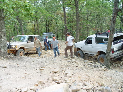 1996 Ford Bronco - Several people are gathered around SUVs navigating a challenging off-road course.