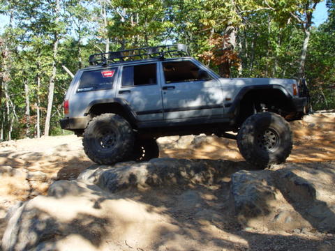 1996 Ford Bronco - This heavily modified Jeep Cherokee XJ navigates a challenging rocky terrain on an off-road trail.