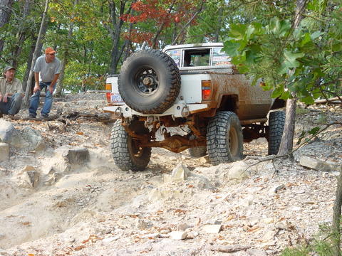 1996 Ford Bronco - An off-road vehicle tackles a challenging rocky trail with two spectators observing the action.
