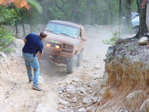 1996 Ford Bronco - A 1996 Ford Bronco tackles a challenging off-road course, kicking up dust as it navigates the rough terrain.