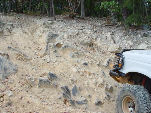1996 Ford Bronco - A white SUV navigates a challenging rocky terrain on an off-road trail.