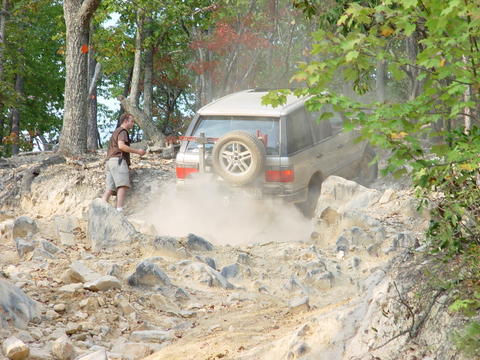 1996 Ford Bronco - An SUV navigates a challenging rocky terrain, kicking up a cloud of dust as it goes.