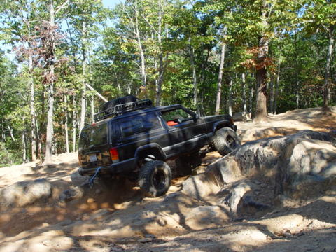 1996 Ford Bronco - This Jeep Cherokee XJ is navigating a challenging off-road course with steep inclines and large rocks.