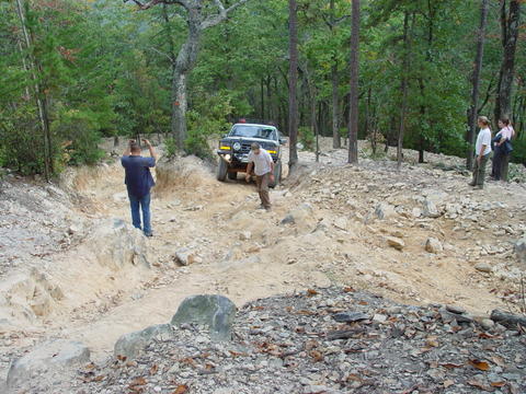 1996 Ford Bronco - A dark green 1992 Ford Bronco navigates a challenging off-road path with onlookers present.
