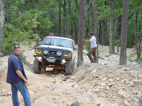 1996 Ford Bronco - A 1996 Ford Bronco navigates a challenging off-road path through a forest.
