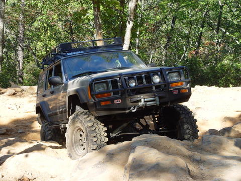 1996 Ford Bronco - A Jeep Cherokee XJ navigates a challenging rocky trail with a winch and roof rack installed.