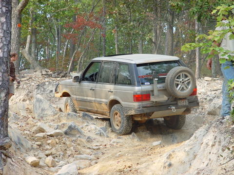 1996 Ford Bronco - A Range Rover navigates a challenging off-road course with a spare tire on the back.