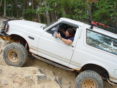1996 Ford Bronco - A white 1996 Ford Bronco is shown off-roading on a challenging rocky trail.