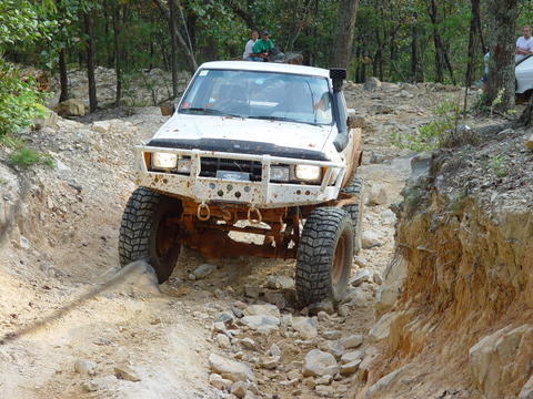 1996 Ford Bronco - An off-road SUV navigates a challenging rocky path, with another vehicle visible in the distance.