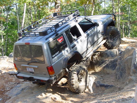 1996 Ford Bronco - This modified Jeep Cherokee XJ is navigating a difficult rocky obstacle on an off-road trail.