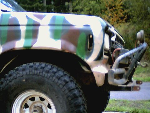 1987 Ford Bronco II - The front corner of a 1987 Ford Bronco II is visible, painted in camouflage with a aftermarket bumper.