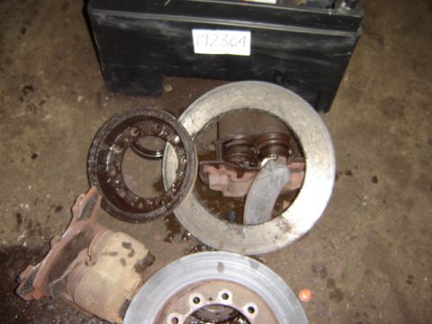 1992 Ford Bronco - Various used brake components are laid out on a concrete floor next to a labeled black box.