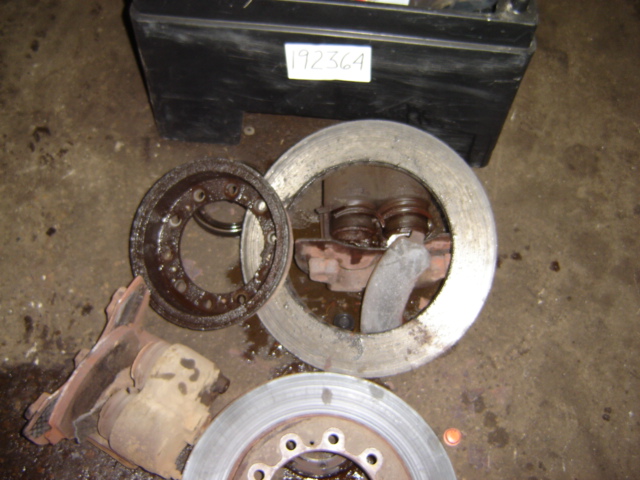 brake rotor, caliper, and drum parts on floor. Black box with 192364 label