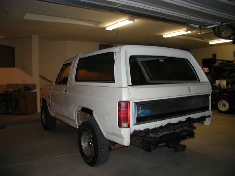 1986 Ford Bronco - A white SUV is parked indoors, showing its rear end and side profile.