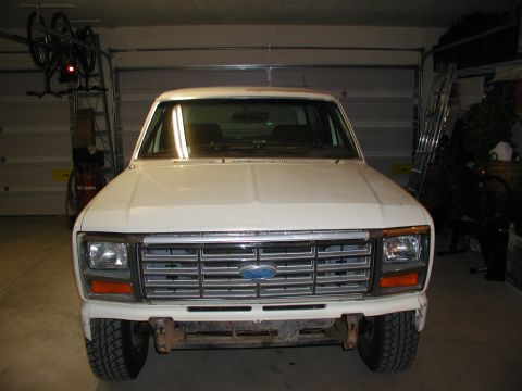 1986 Ford Bronco - The front grille and headlights of a white pickup truck are visible in this image.