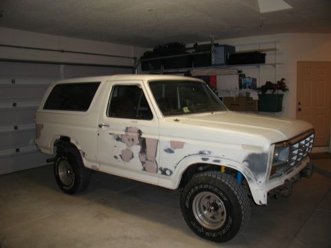 1986 Ford Bronco - This white SUV, likely from the 1980s, is viewed from the front-right angle inside a garage.