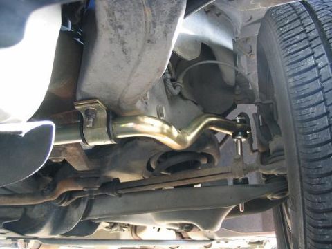 1999 Ford Crown Victoria - Close-up view of the underbody suspension system, highlighting a gold-colored sway bar and related components.