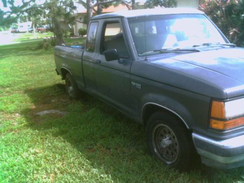 1990 Ford Ranger - A dark green Ford Ranger pickup truck is parked on a grassy area with trees and a house in the background.